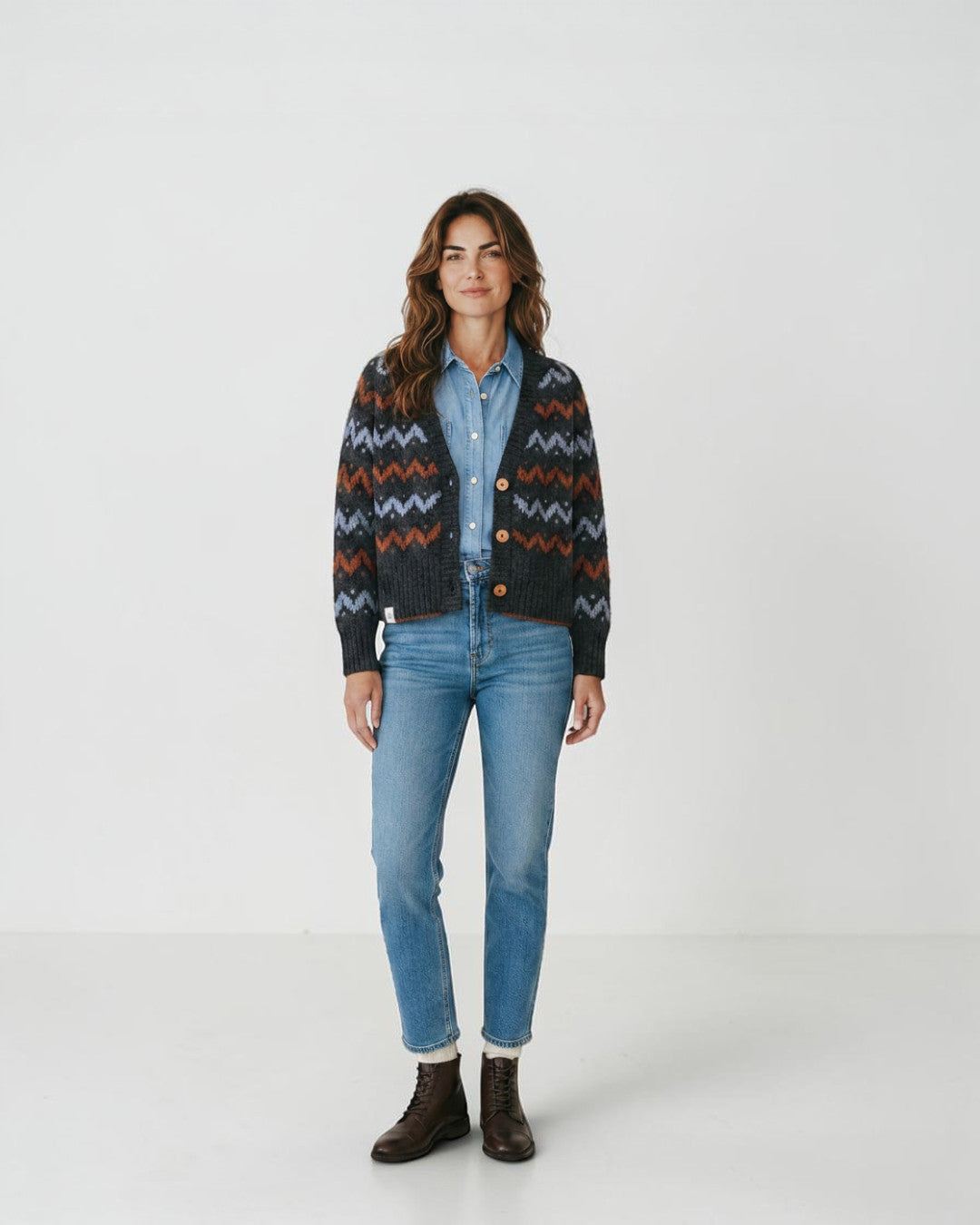 Modelo vistiendo cárdigan de punto Lalura Design con patrón geométrico en zigzag gris, azul y naranja y botones madera