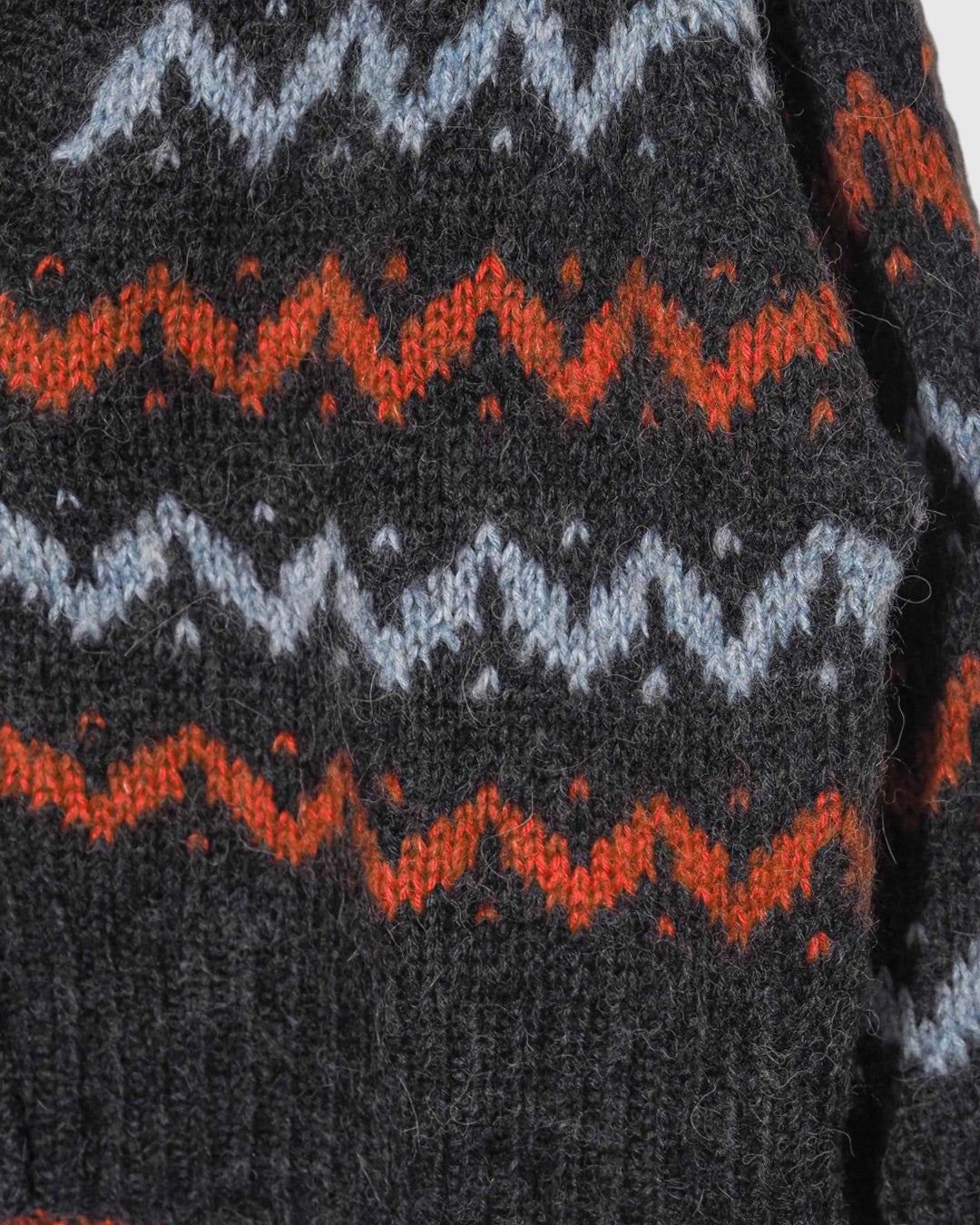 Cárdigan de punto Lalura Design con patrón geométrico en zigzag gris, azul y naranja, textura suave y cálida.
