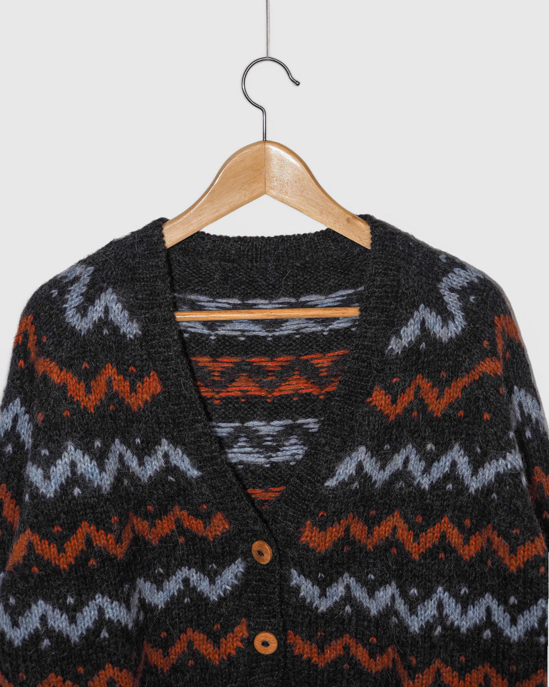 Cárdigan Lalura Design de punto grueso con patrón geométrico en zigzag gris, azul y naranja y botones de madera.