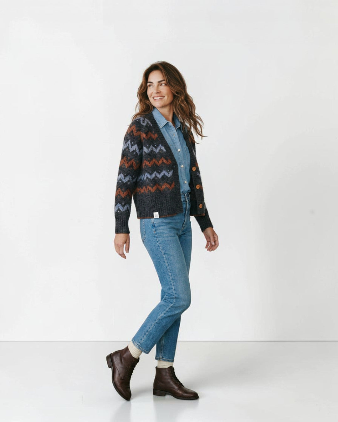 Modelo vistiendo cárdigan Lalura Design de punto grueso con patrón geométrico en zigzag gris, azul y naranja.